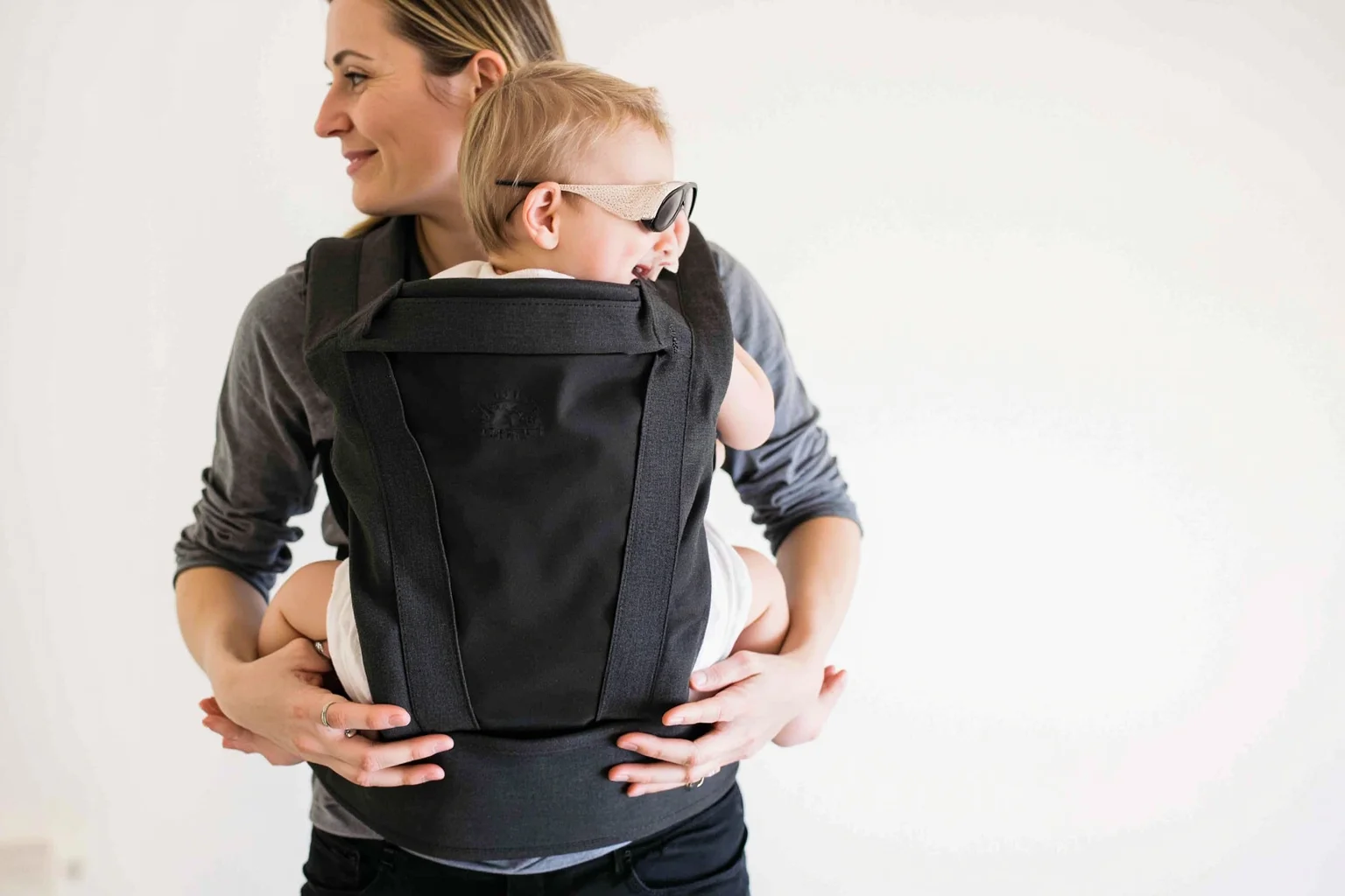 Soft-structured baby carrier with infant positioned securely against caregiver's body