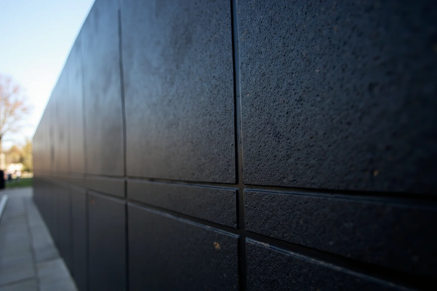 Solemn illustration of a black stone memorial wall engraved with names