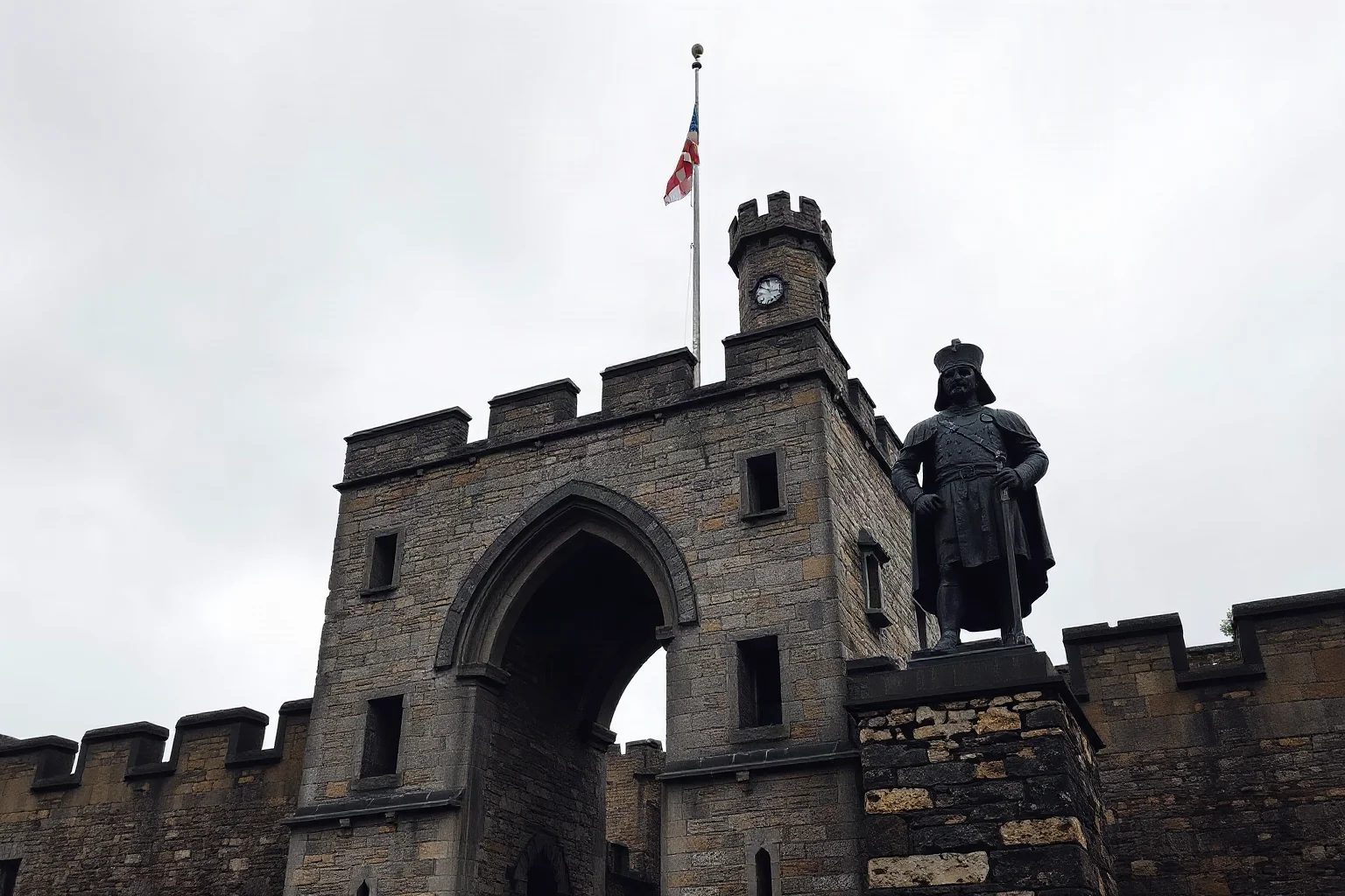 Stone castle gatehouse with a stern medieval guard silhouette, overcast grey sky