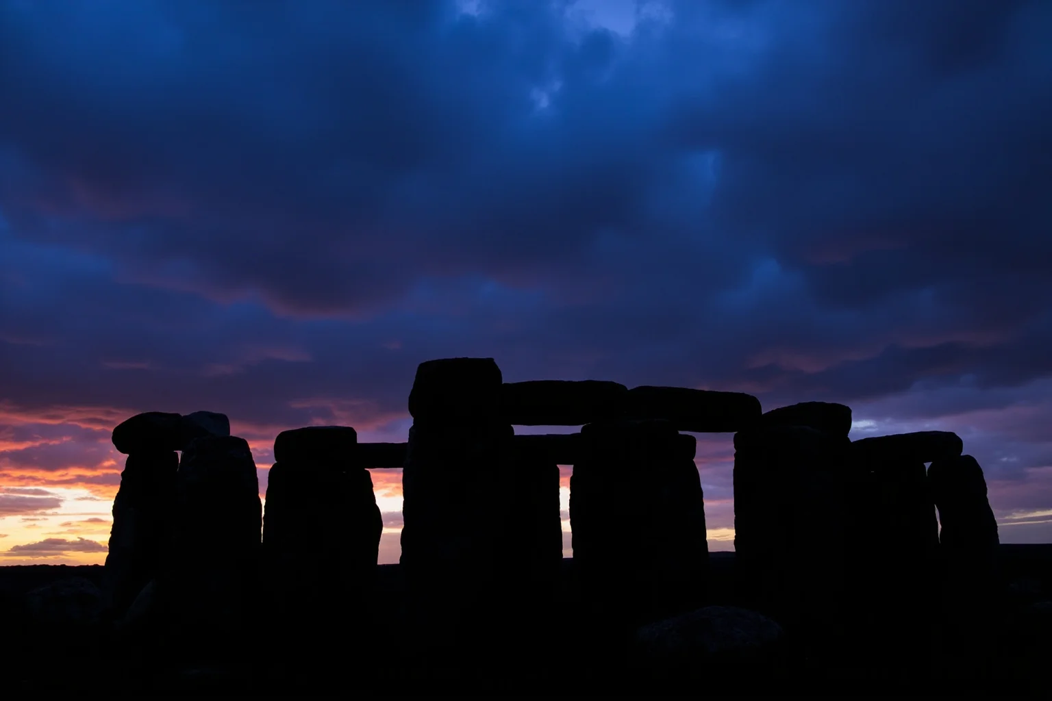 Stonehenge's massive stone circle silhouetted against a dramatic sky at dawn