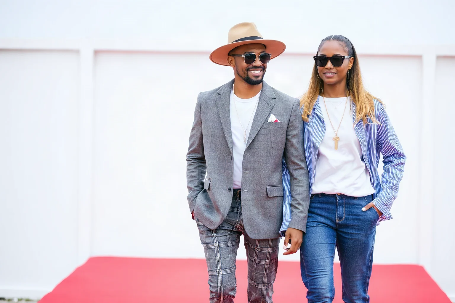 Stylish modern celebrity couple in high-fashion outfits walking together on a red carpet