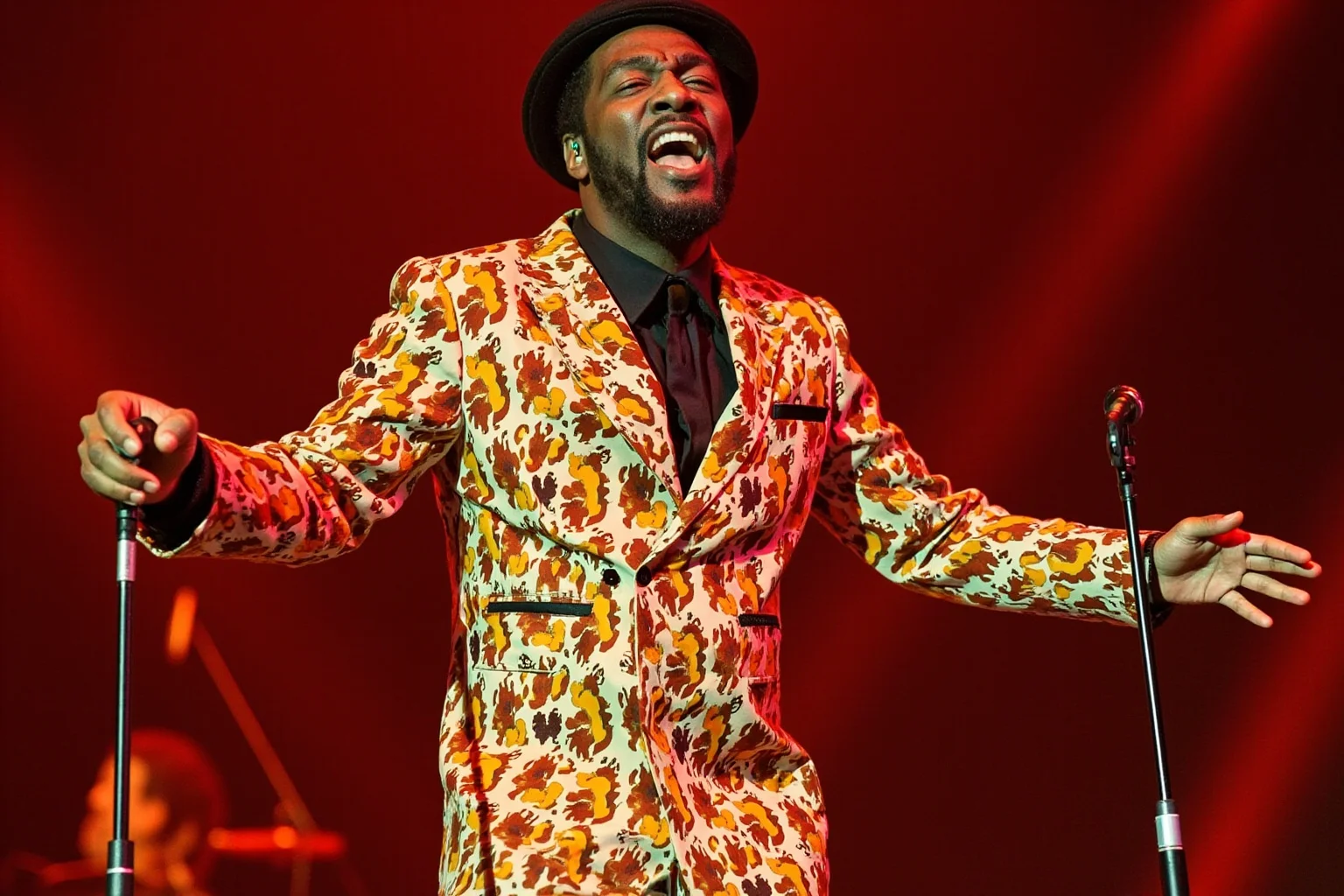 Stylized illustration of a 1970s soul singer performing passionately on stage in a patterned suit, warm retro colors