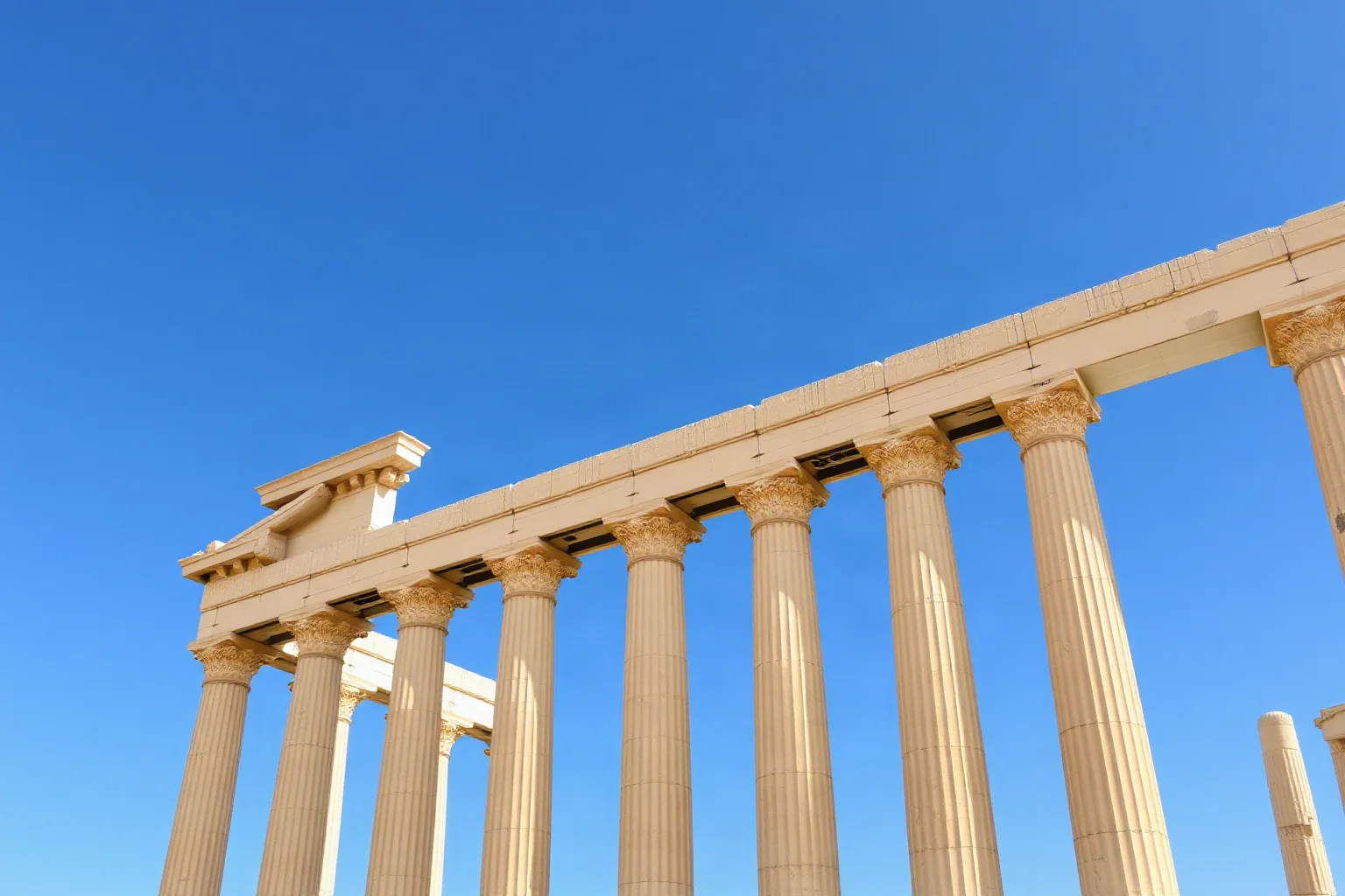 Tall standing Corinthian columns of the Temple of Olympian Zeus in Athens against a blue sky