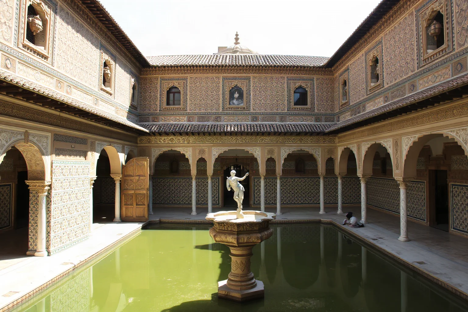 The Alhambra in Granada showing intricate Islamic geometric tilework, carved stucco, and a reflecting pool courtyard