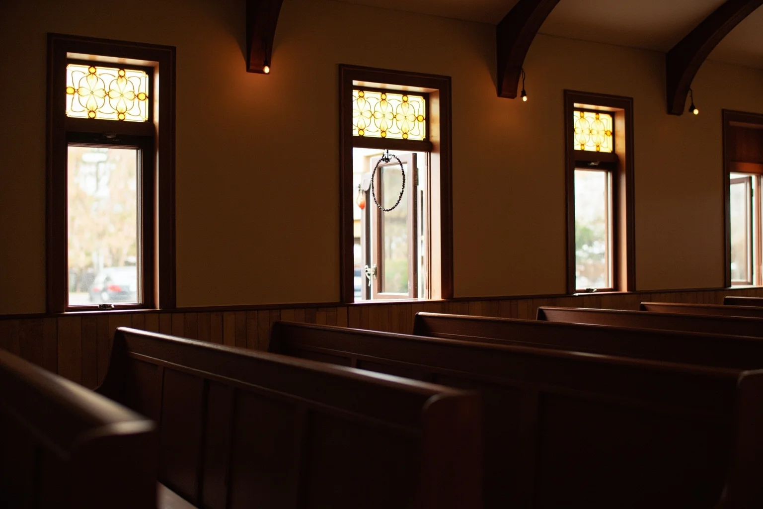 The interior of a small Southern Pentecostal church with wooden pews and warm light through windows