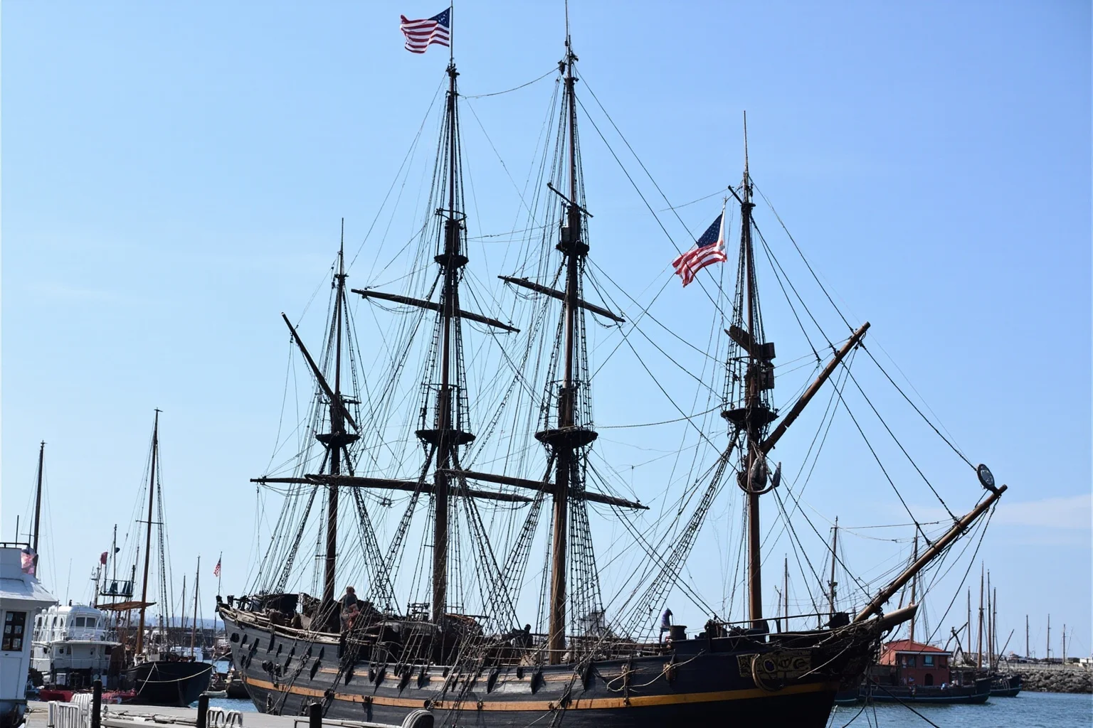 The Longest-Serving Warships of All Time 2 Historic wooden sailing frigate with tall masts and American flag, moored in a New England harbor, 18th-century style warship