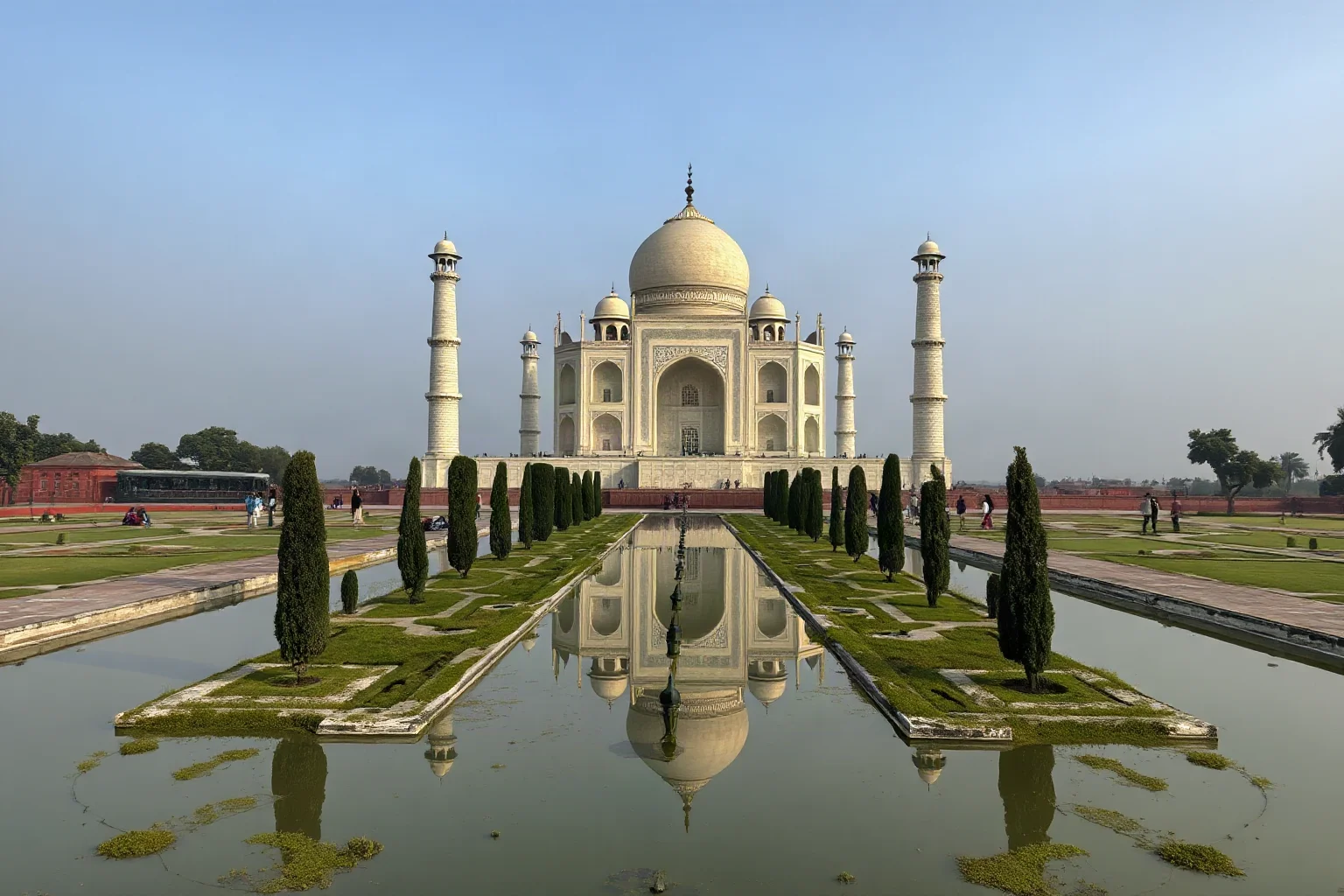 The Taj Mahal marble mausoleum with its iconic dome and symmetrical gardens reflected in still water