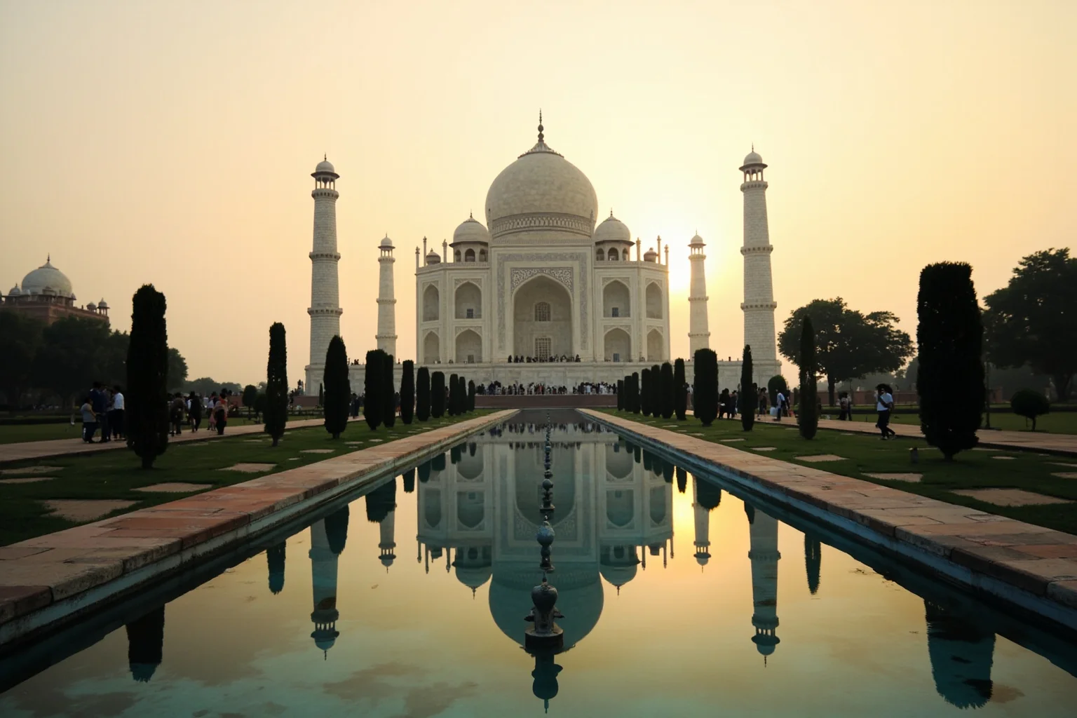 The Taj Mahal's white marble dome reflected in a still garden pool at dawn