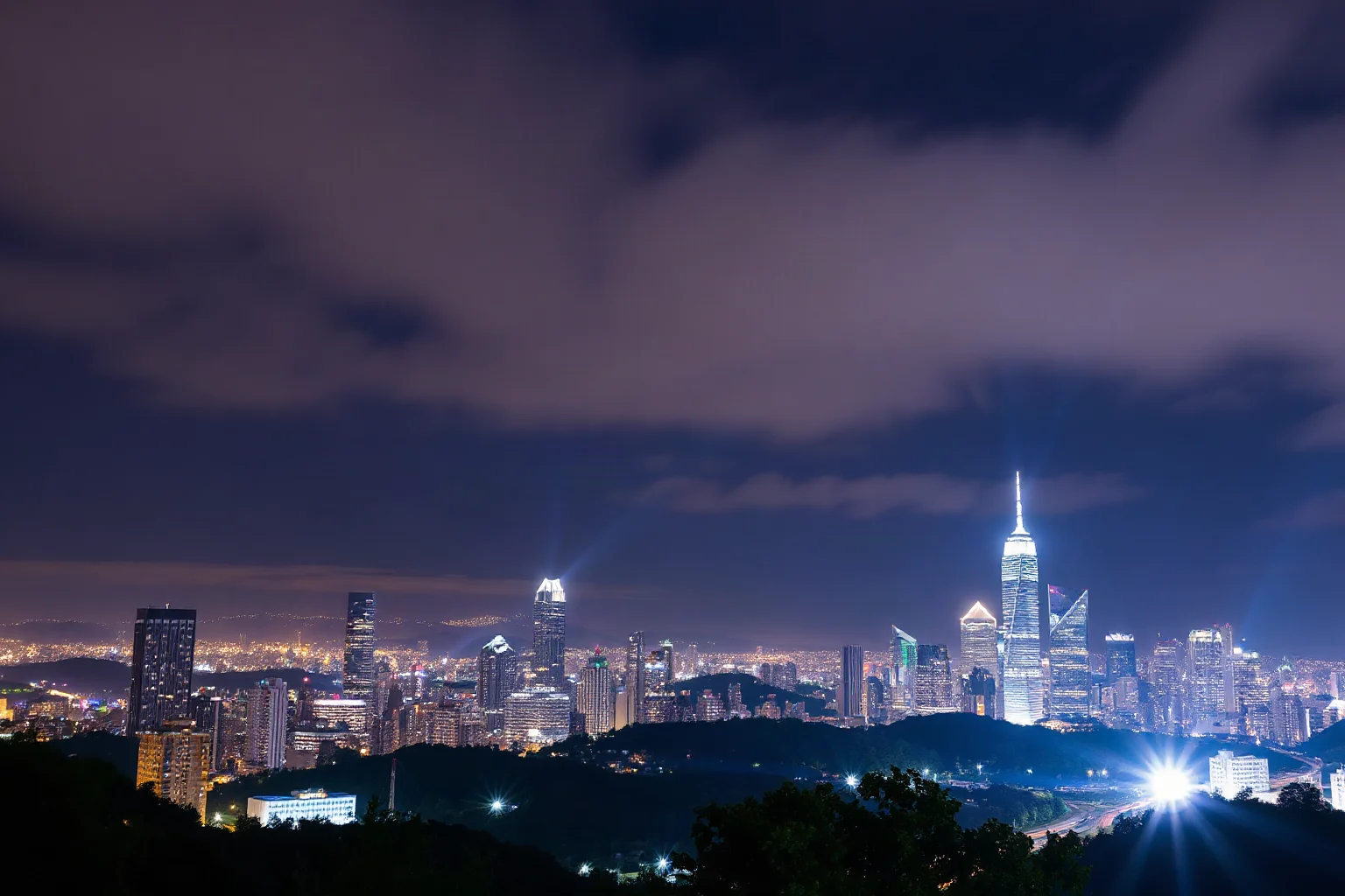 Two empty illuminated light beams rising into a night sky over a city skyline, memorial style, no specific landmarks