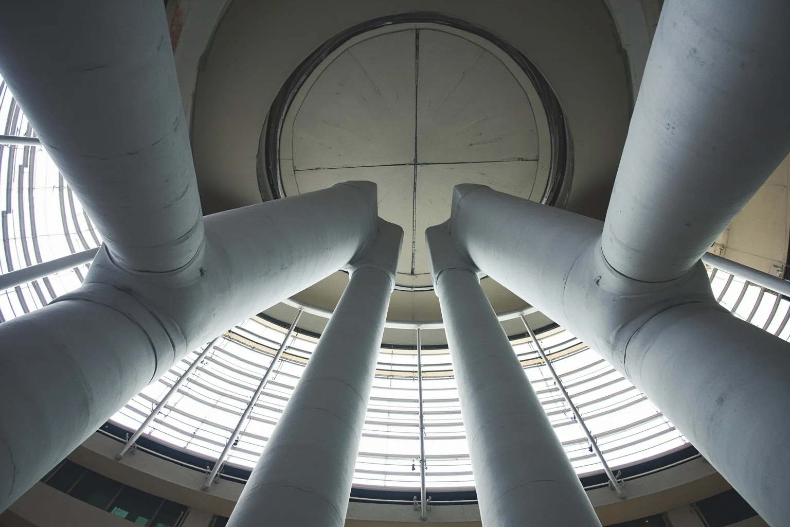 Two enormous tapered steel facade columns rising toward a museum ceiling
