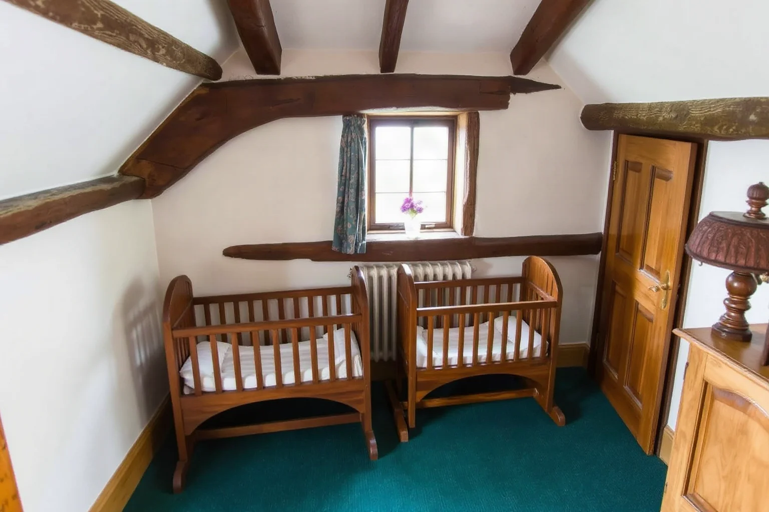 Two small Elizabethan-era baby cradles side by side in a modest timber-framed cottage room