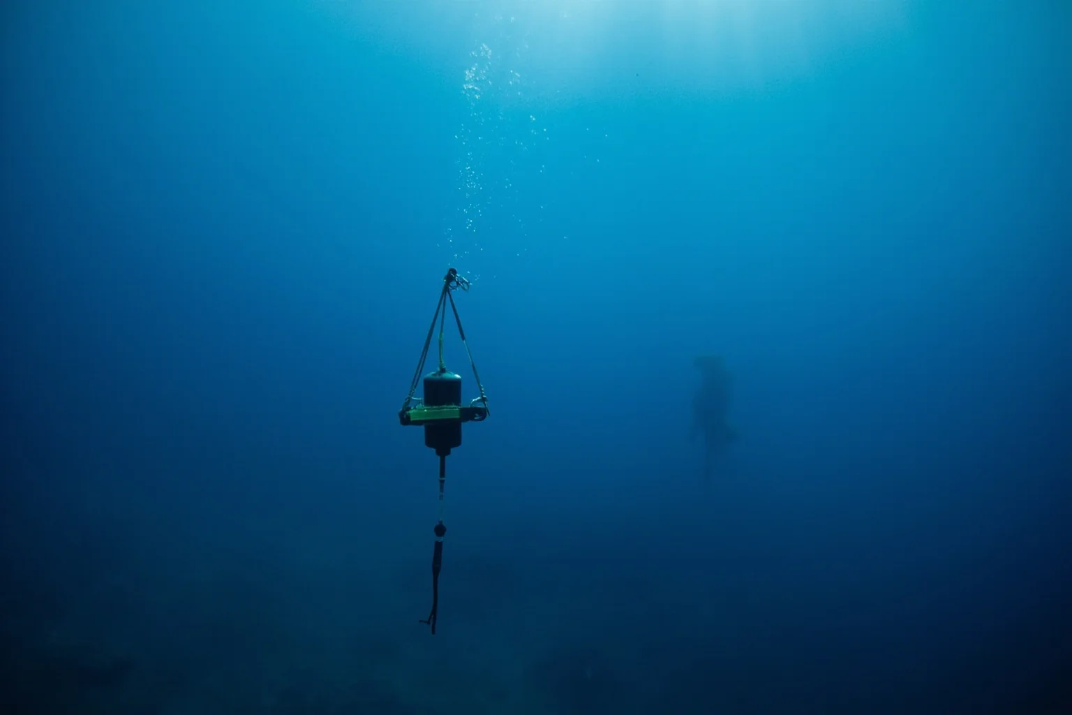 22 Ocean Mysteries We Still Haven't Solved 7 Underwater scene of a hydrophone device suspended in deep blue water listening for distant sounds