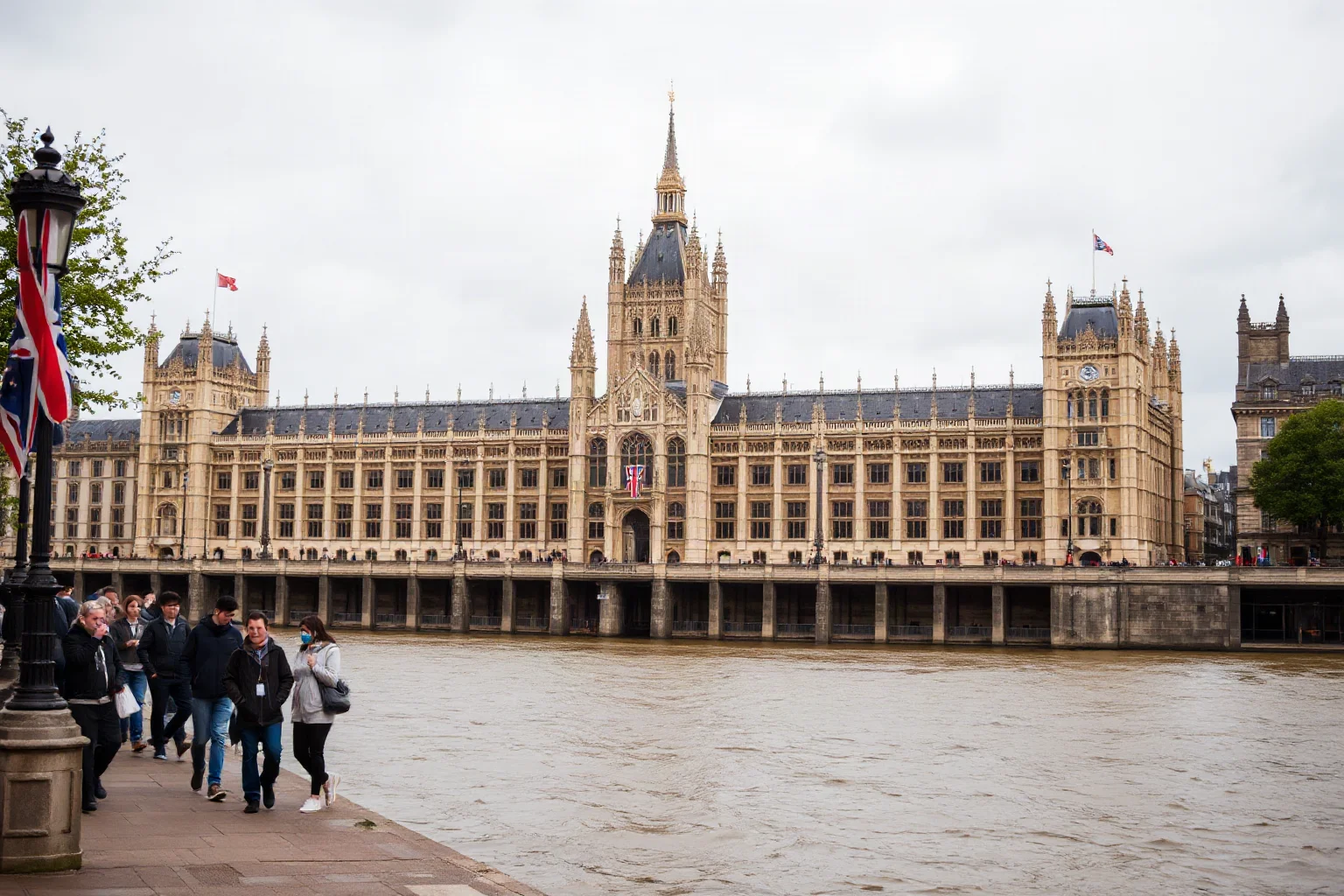 Victorian-era British Parliament building beside a filthy, foul river with people covering their noses