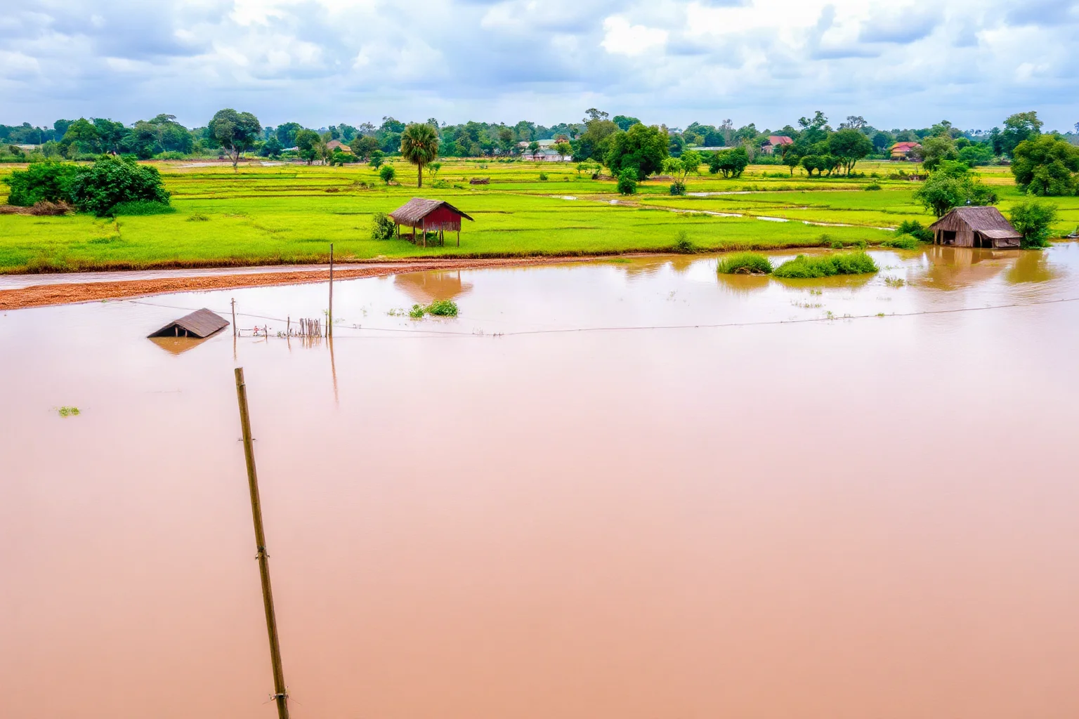 Watercolor-style scene of a flooded river basin with submerged fields and huts