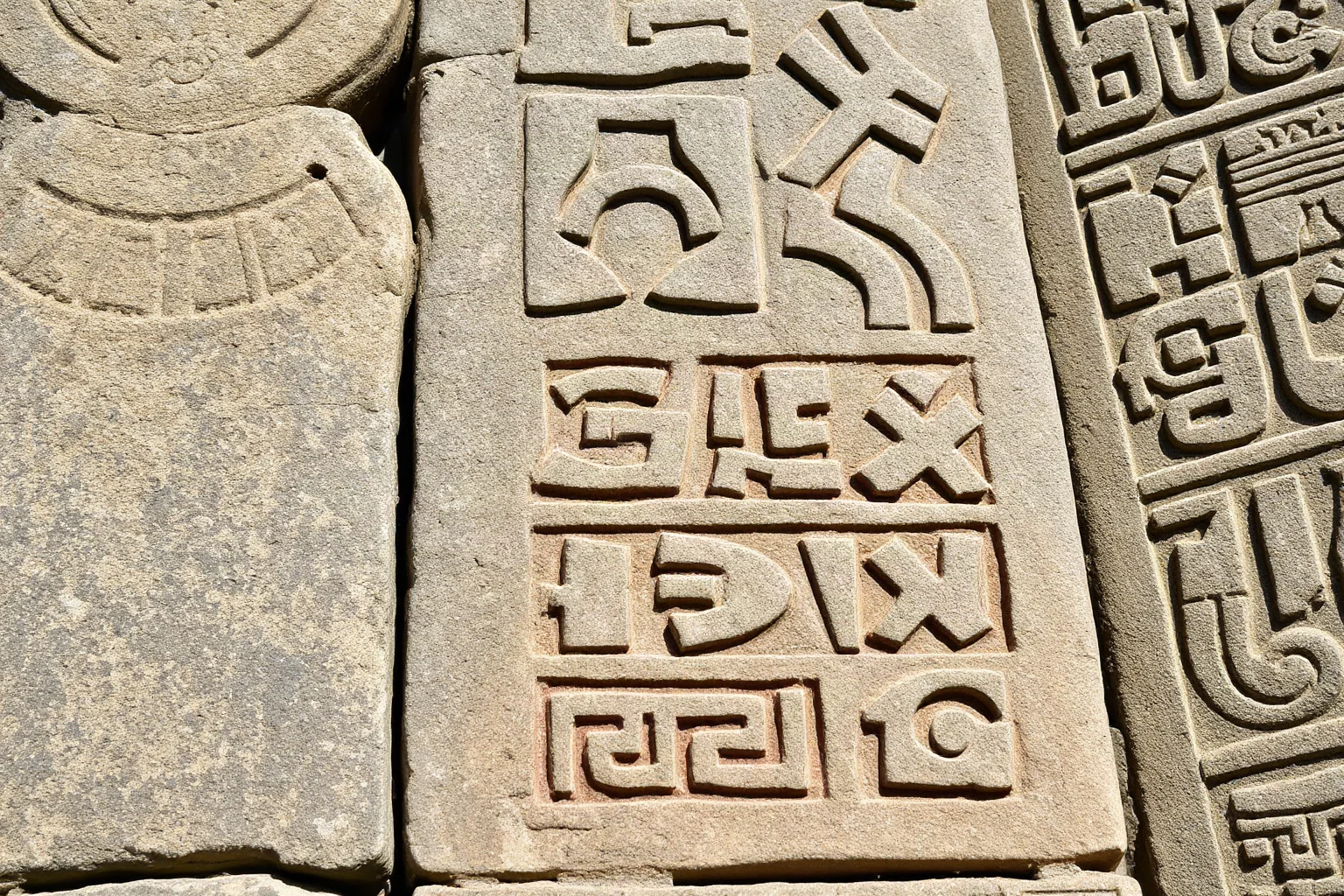 Weathered Maya stone stela covered in detailed hieroglyphic carvings