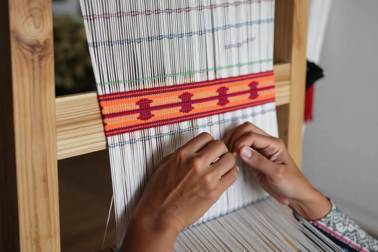 Weaver using a backstrap loom to create colorful patterned cotton textile