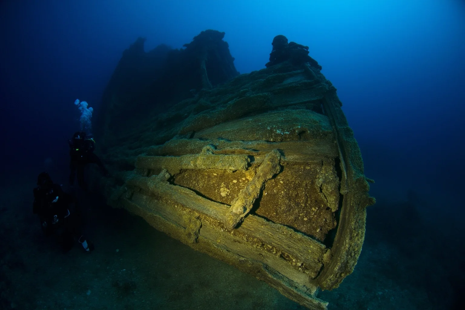 22 Coolest Underwater Discoveries Made Throughout History 10 Well-preserved 17th-century wooden warship hull illuminated underwater with divers nearby