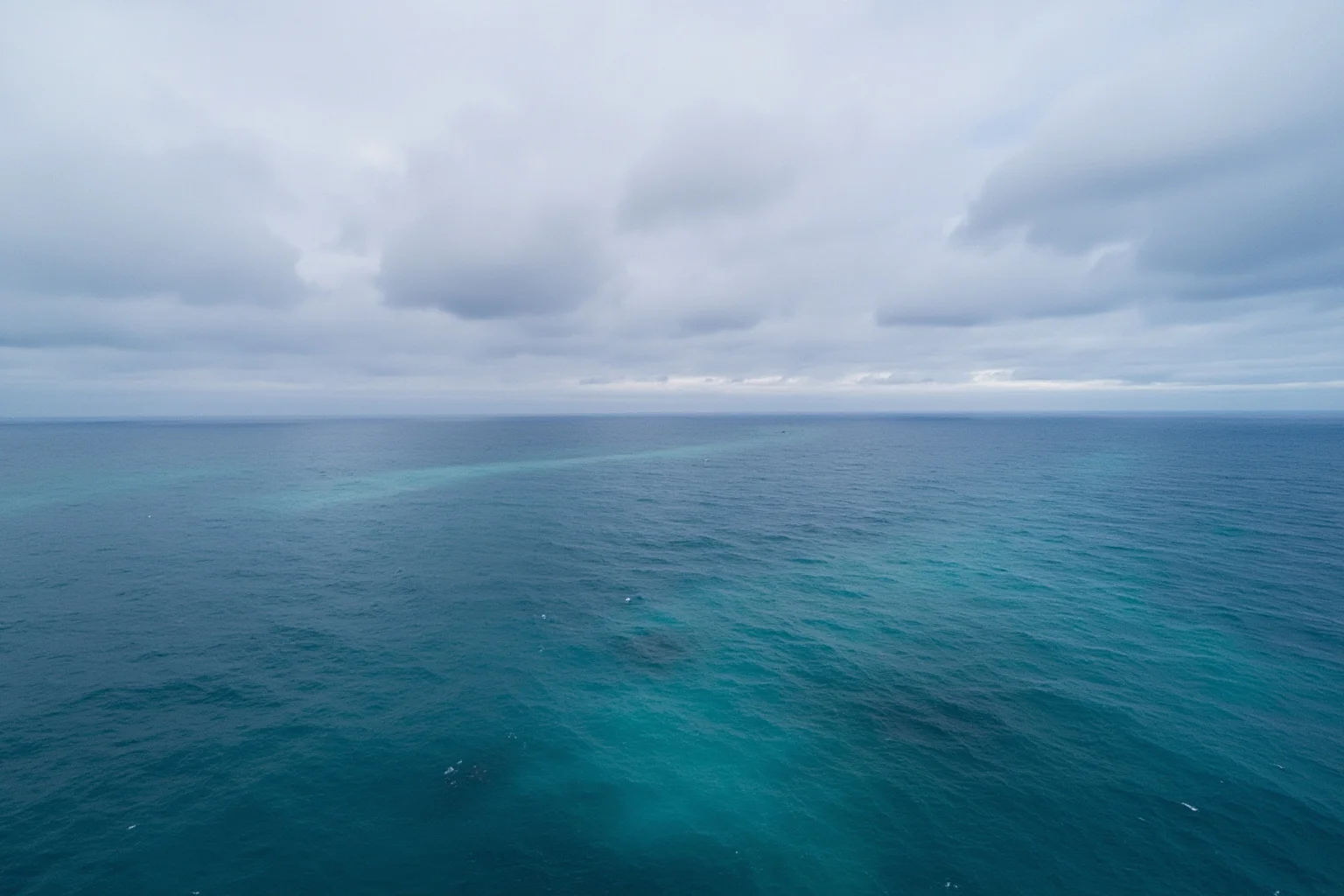 22 Ocean Mysteries We Still Haven't Solved 21 Wide aerial shot of a vast, empty, unmapped-looking deep ocean under a cloudy sky