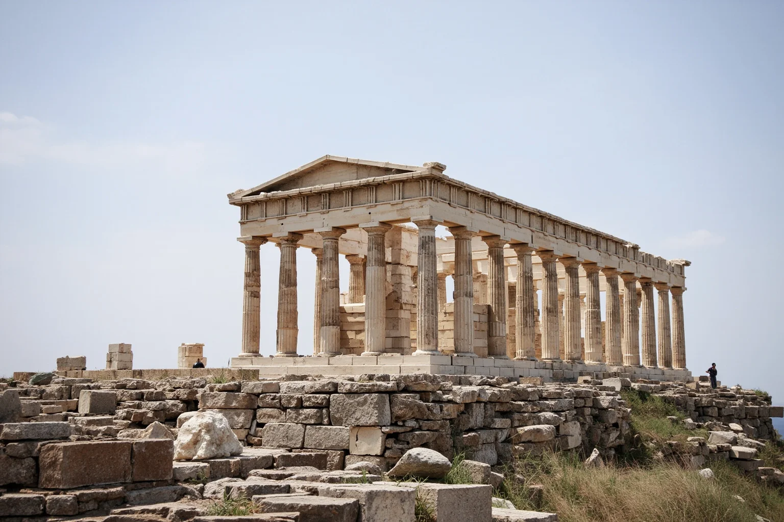 Wide-angle view of a large ancient Greek marble temple with rows of columns on a rocky hilltop