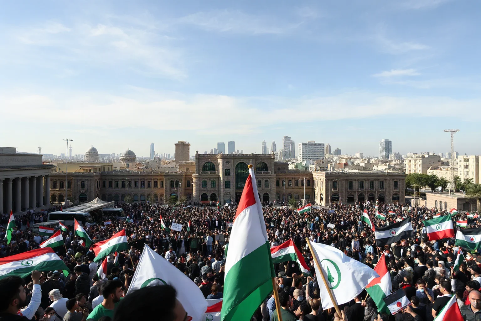 Wide city square filled with protesters holding national flags under a clear sky, Middle Eastern city skyline
