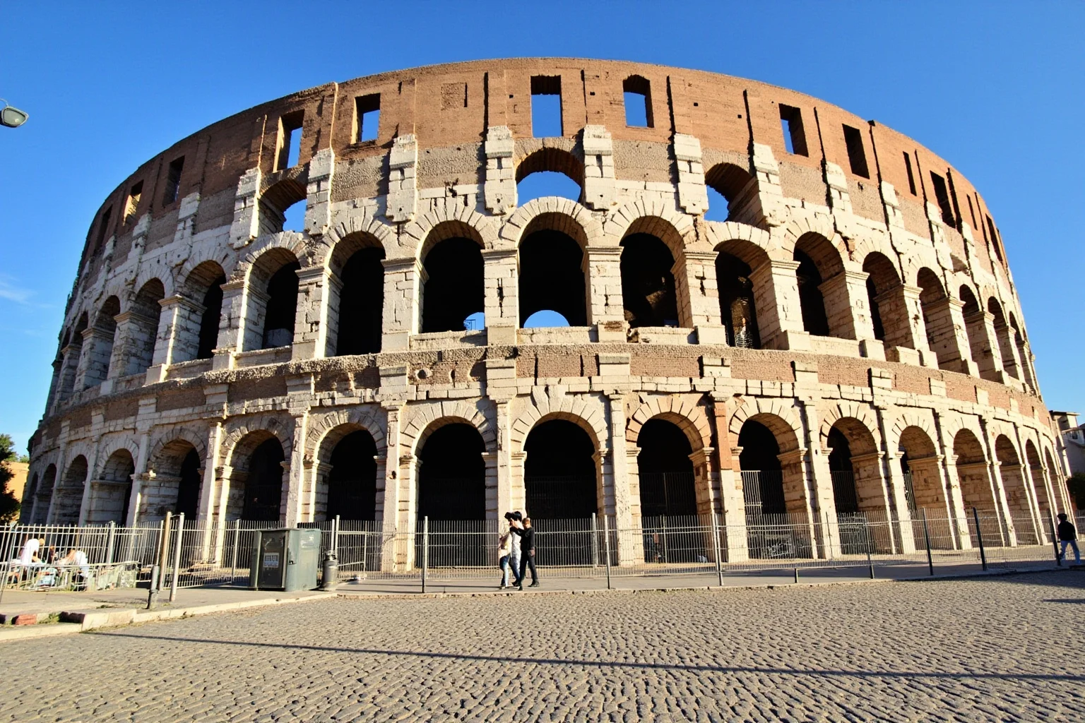 Wide exterior view of the elliptical multi-tiered Colosseum showing arches and classical columns