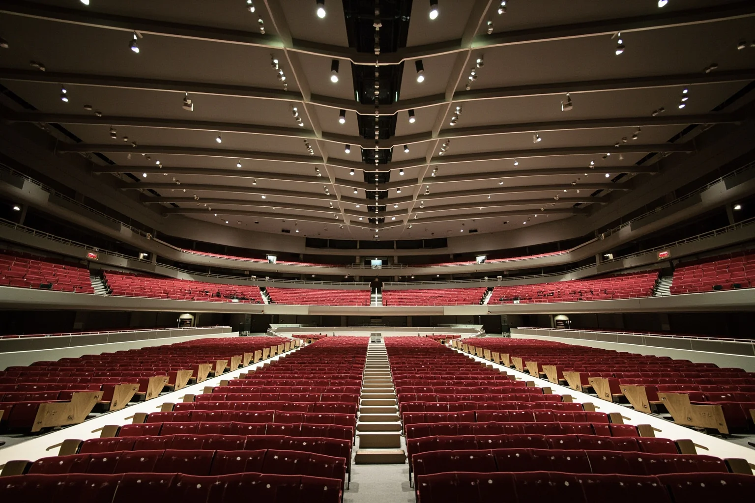 Wide interior view of a large modern auditorium hall with curved concrete ceiling beams and rows of seating