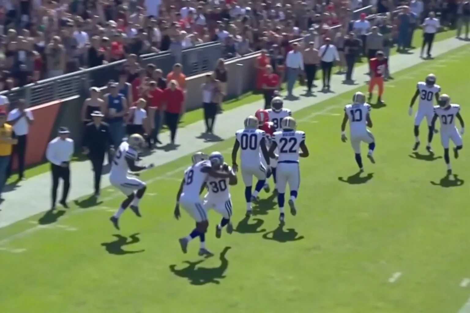 A 100-yard interception return along the sideline, generic uniforms, no real logos or names, defenders trailing behind.