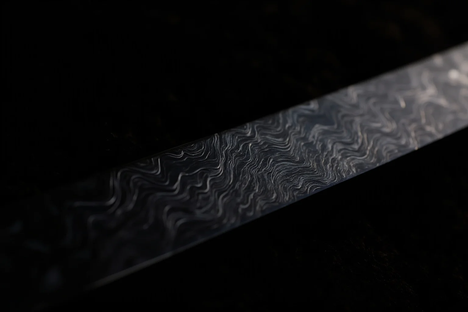 A close-up of a wavy-patterned steel sword blade with a distinctive damascus pattern, lying on a dark velvet cloth, dramatic side lighting.