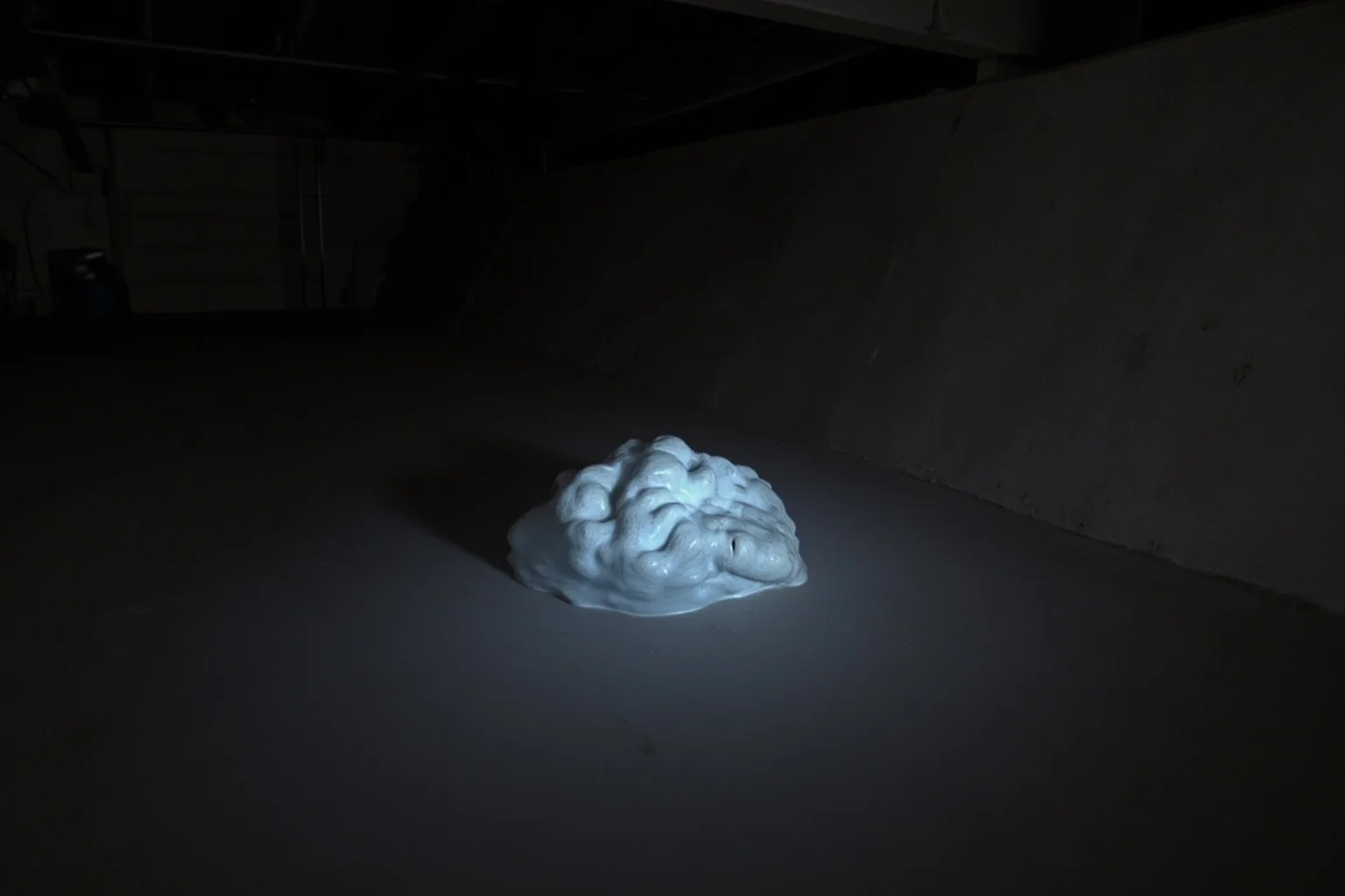 A dark basement scene with a large, wrinkled, foot-shaped mass of solidified melted material, glowing faintly, labeled 'elephant's foot' in a caption style.