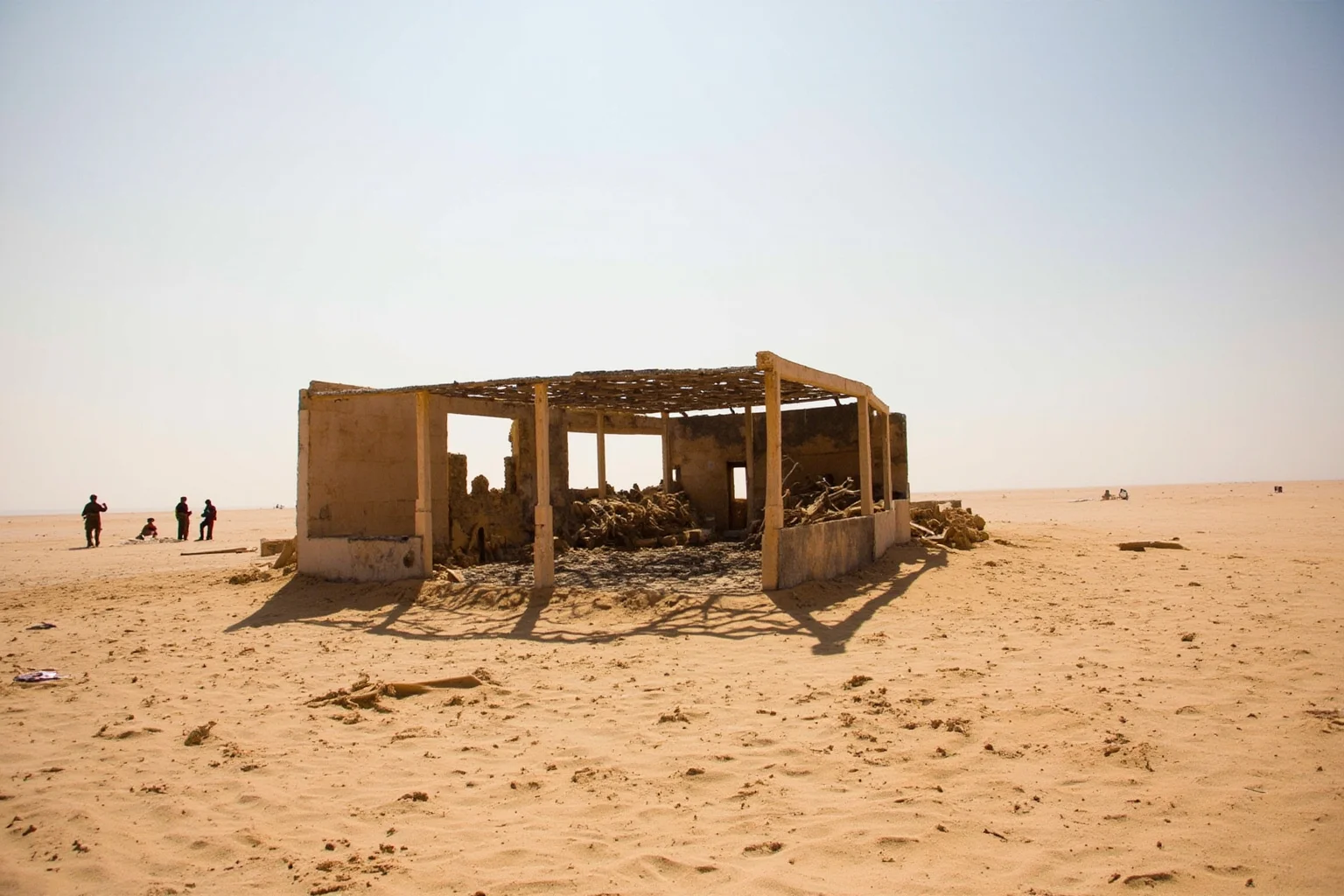 22 Evil Dictators Who Were Eventually Overthrown 19 A desert compound with a burnt-out bunker and rebel fighters in the distance, Libya 2011, no faces.