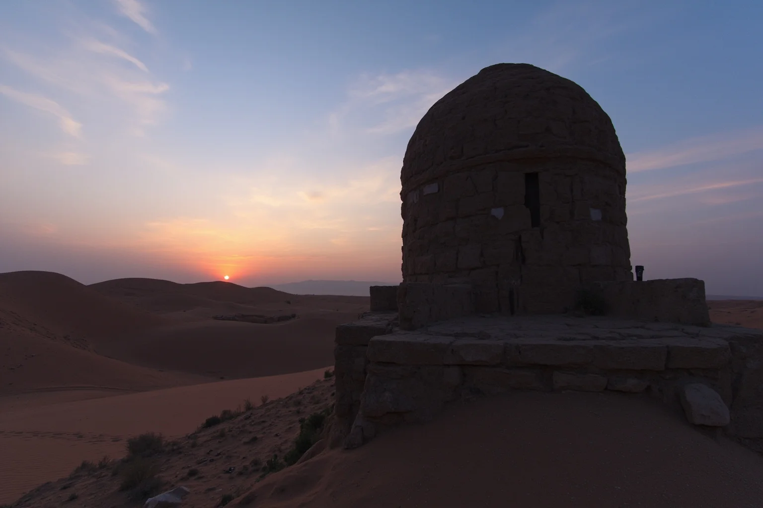 A domed Persian yakhchal ice house standing in a desert landscape at dusk