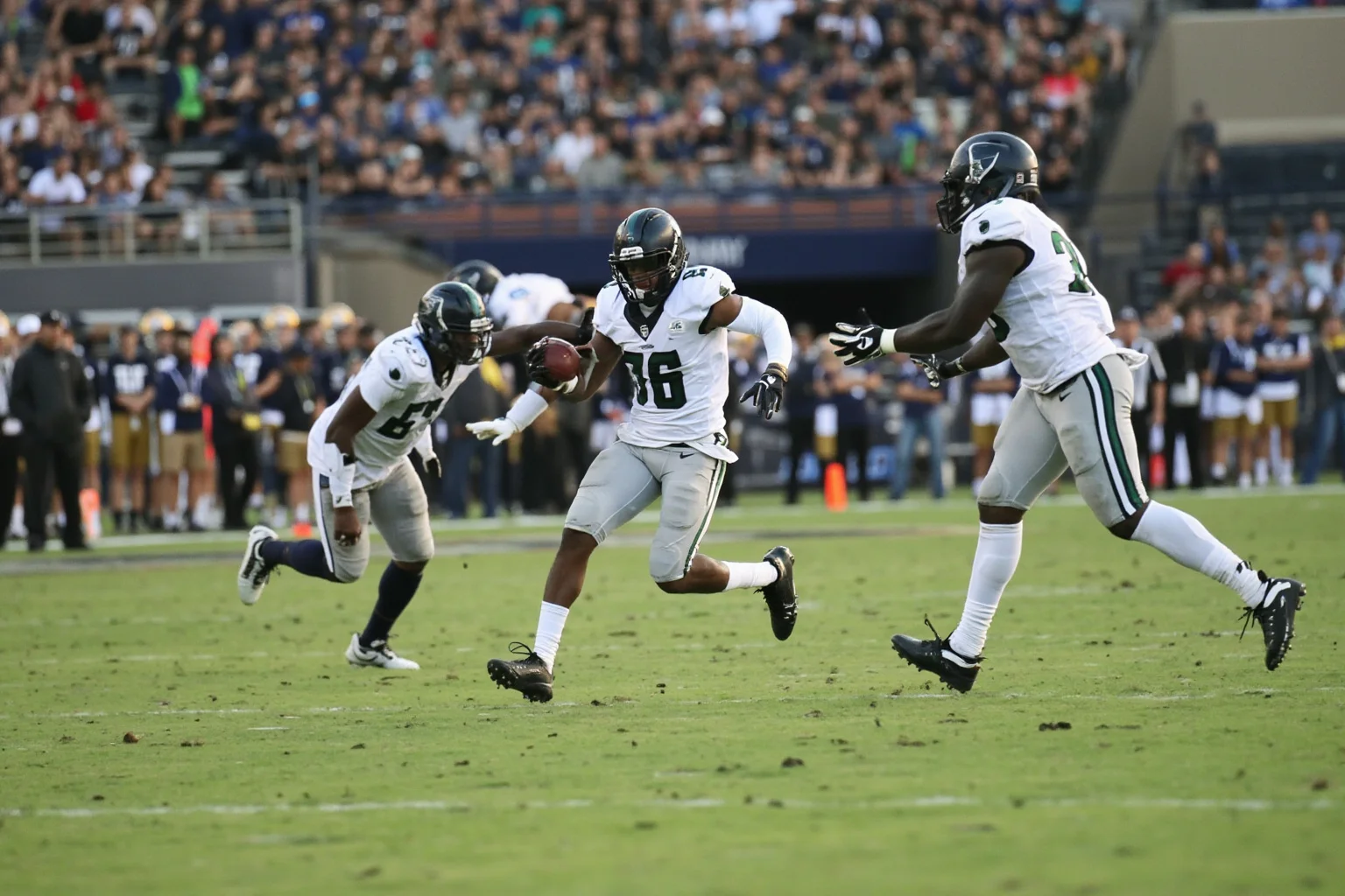 A fumble recovery by a defender in the open field, generic uniforms, no real logos or names, fourth-quarter tension.