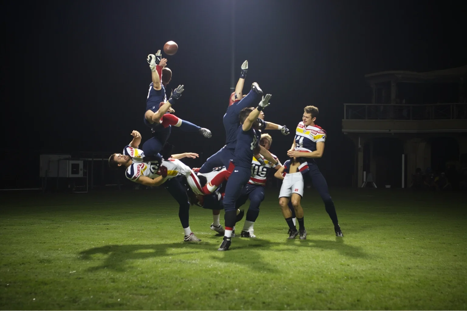 A juggling circus catch by a receiver falling to the turf, generic uniforms, no real logos or names, dramatic lighting.