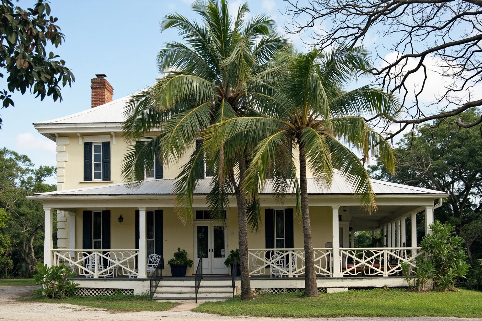 A mid-20th-century Caribbean plantation house with palm trees and a veranda, no people visible.