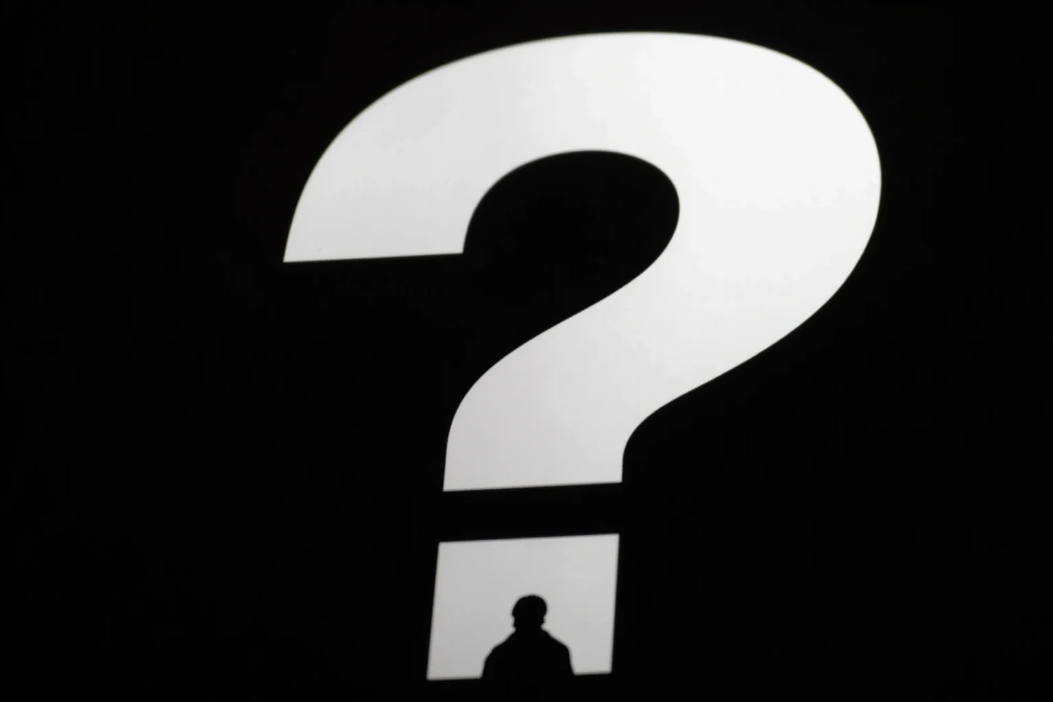 A question mark over a silhouette of a spy.