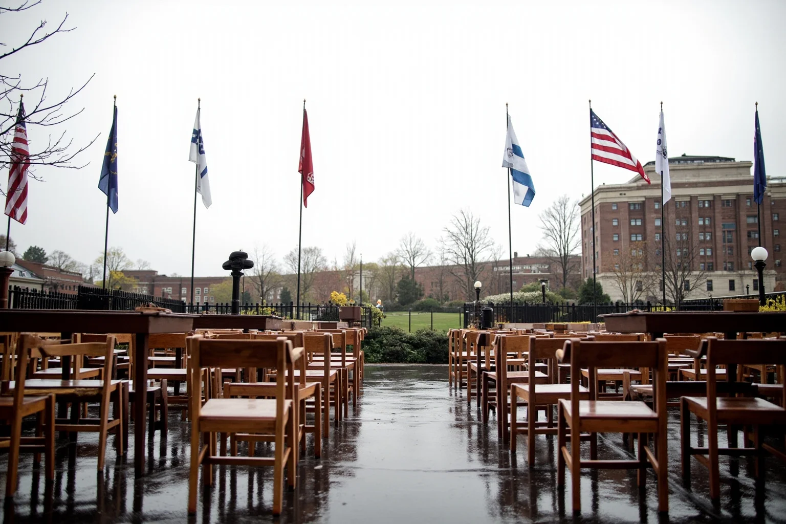 A rain-soaked inaugural platform with wet flags and empty wooden chairs, overcast sky, no people.