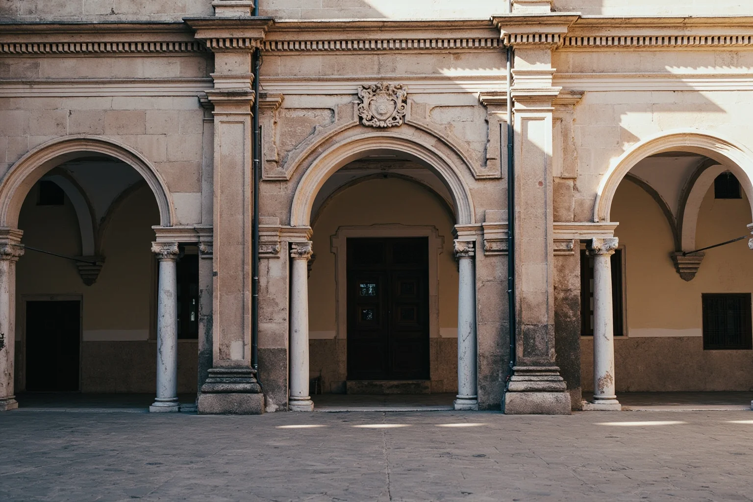 Old Money: 24 Hidden Dynasties That Shaped the Course of History 3 A Renaissance Florentine palazzo courtyard with arched colonnades and a family coat of arms carved in stone, soft morning light, no people, architectural photograph style.