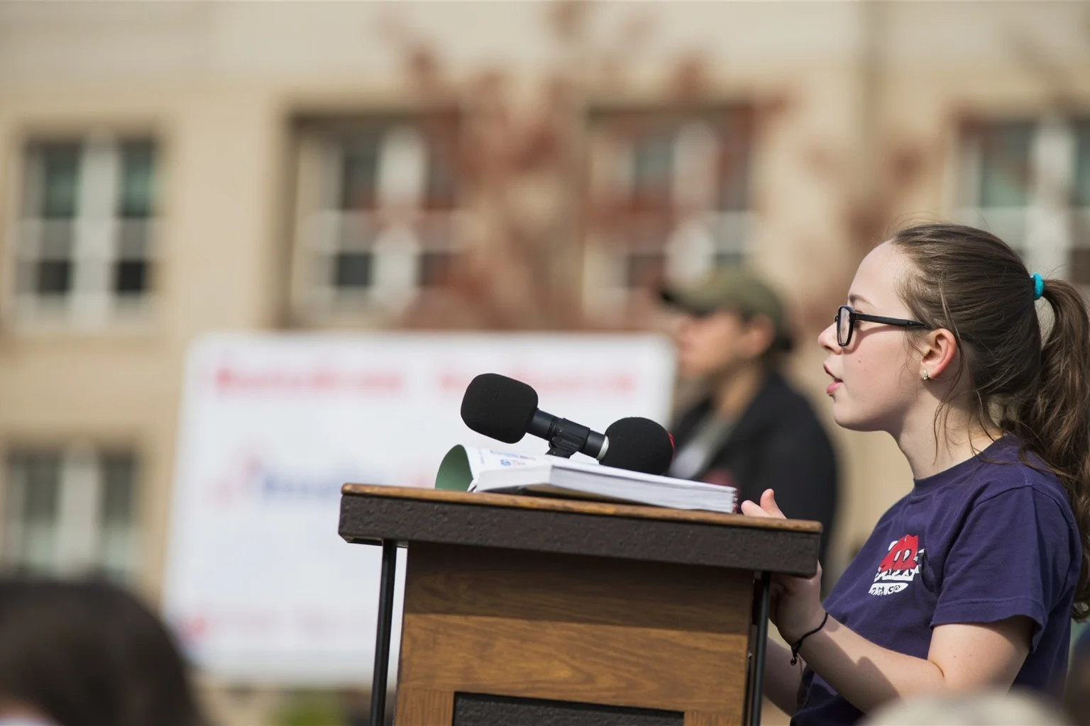 The Greatest Underdog Stories in History: 20 Unlikely Wins That Still Inspire 20 A teenage girl speaking at a podium with books and a school building in the background, symbolic education advocacy scene, no identifiable faces.