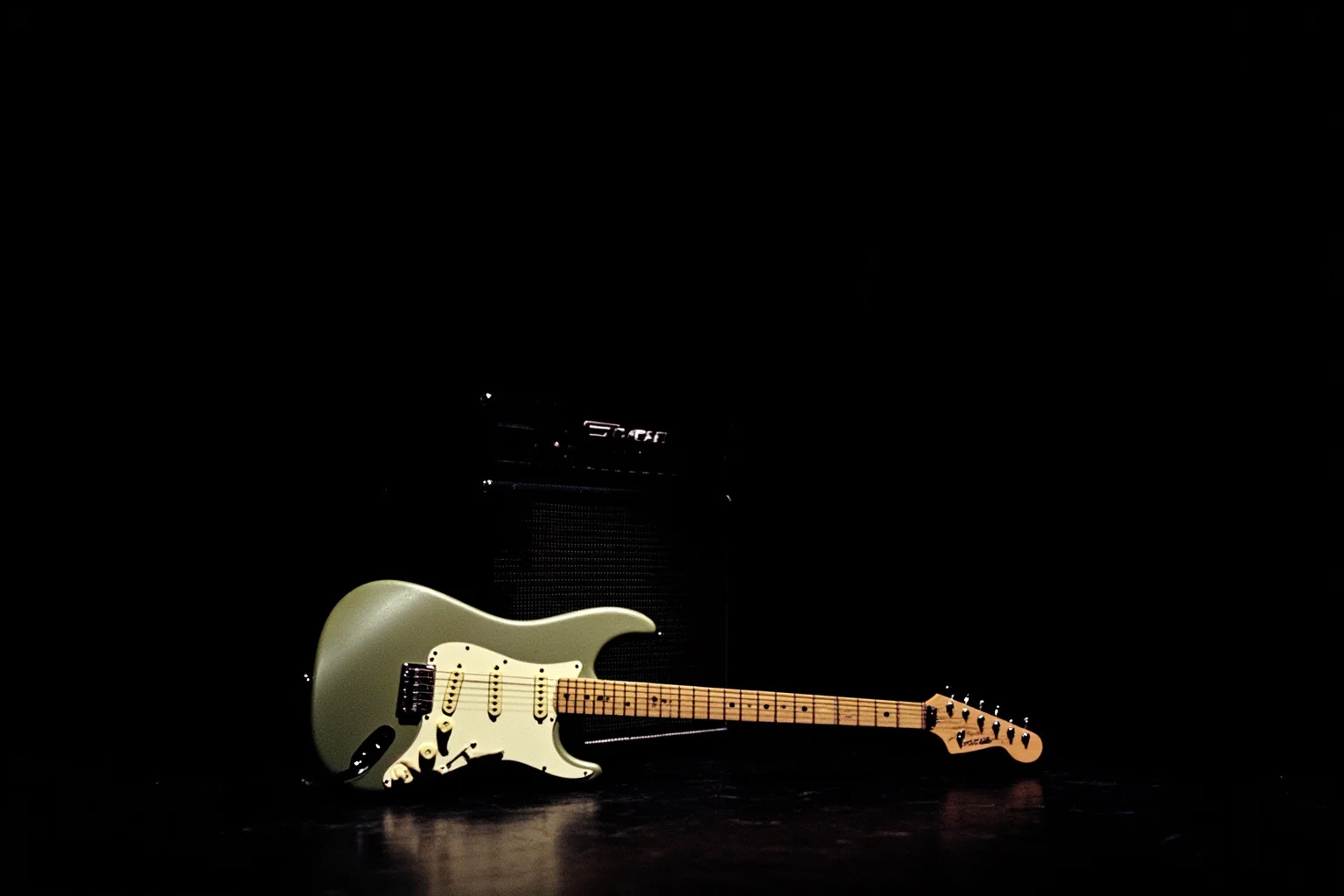 A vintage Fender Stratocaster guitar leaning against an amplifier on a dark stage, single spotlight, 1990s concert atmosphere