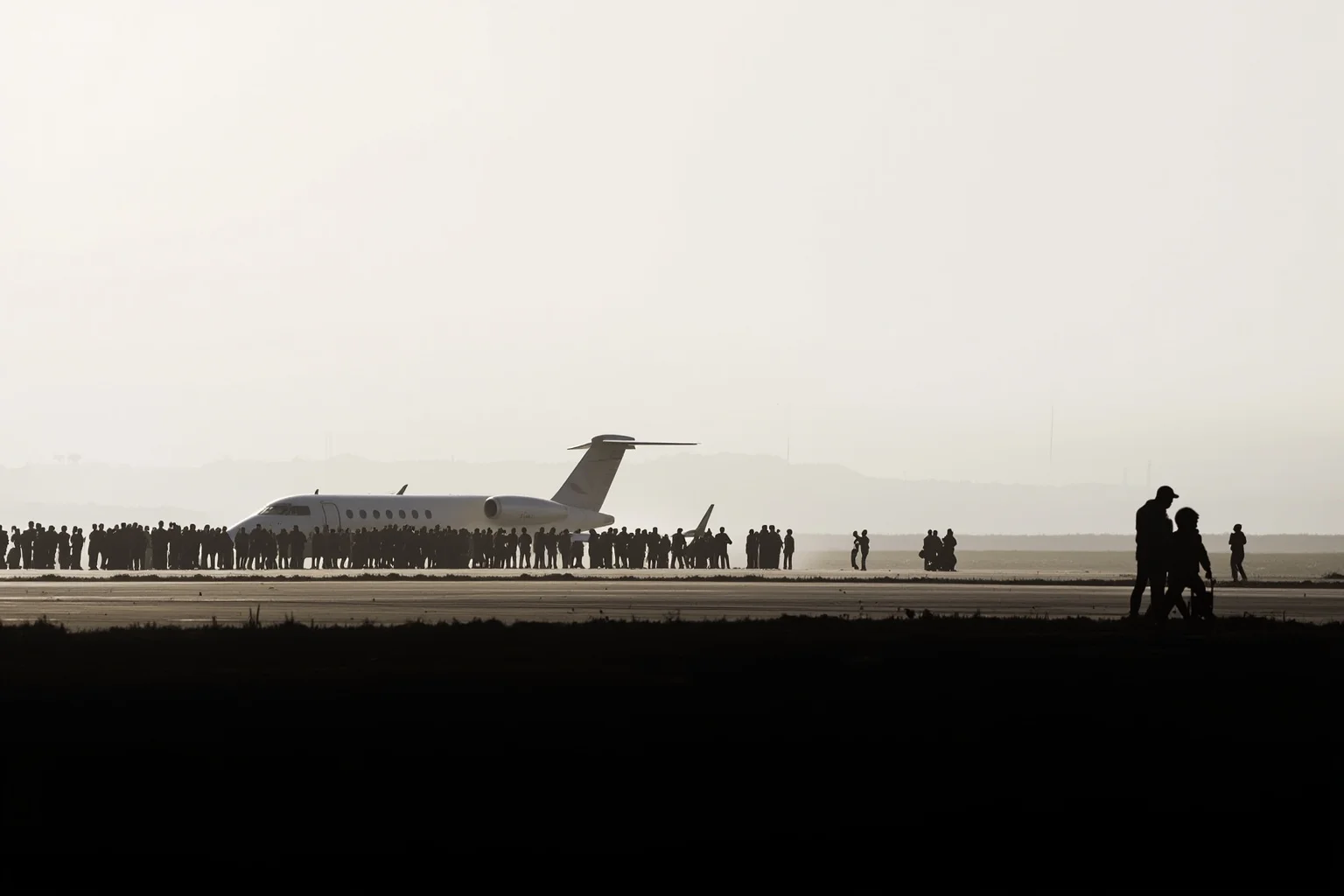 22 Evil Dictators Who Were Eventually Overthrown 23 A West African airport runway with a private jet and a crowd, 2017, distant silhouettes only.
