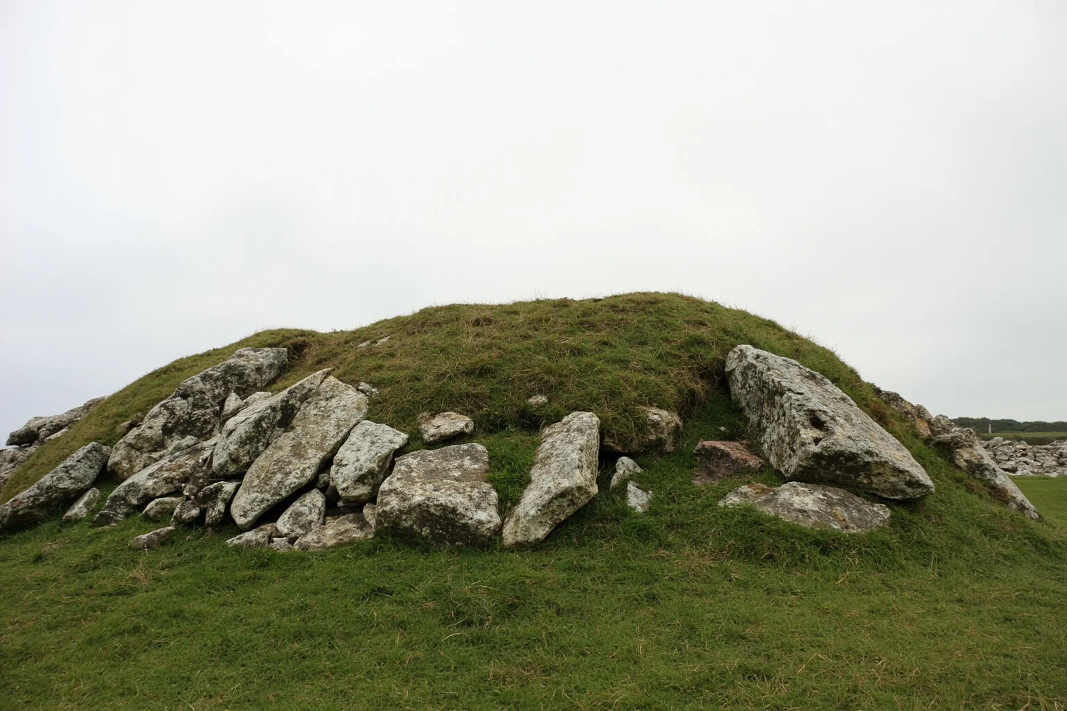 22 Oldest Monuments Found Around the World 4 Massive Neolithic burial cairn of Barnenez in Brittany, France, with grass-covered stone mound under overcast sky