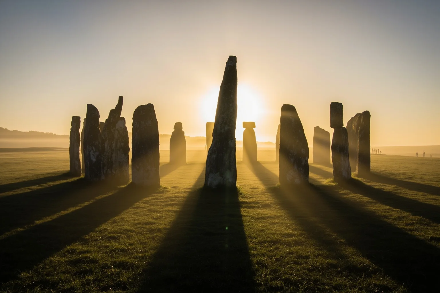 Massive standing stones arranged in a circle on a misty English plain at sunrise, long shadows