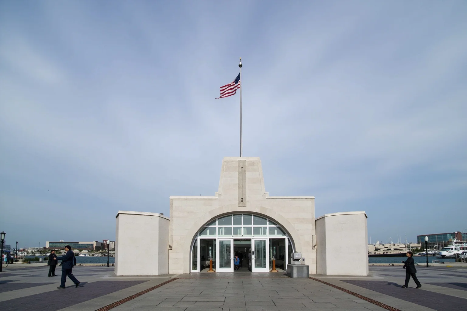 National memorial entrance with flag at half-mast over a Pacific harbor, modern day, respectful and serene