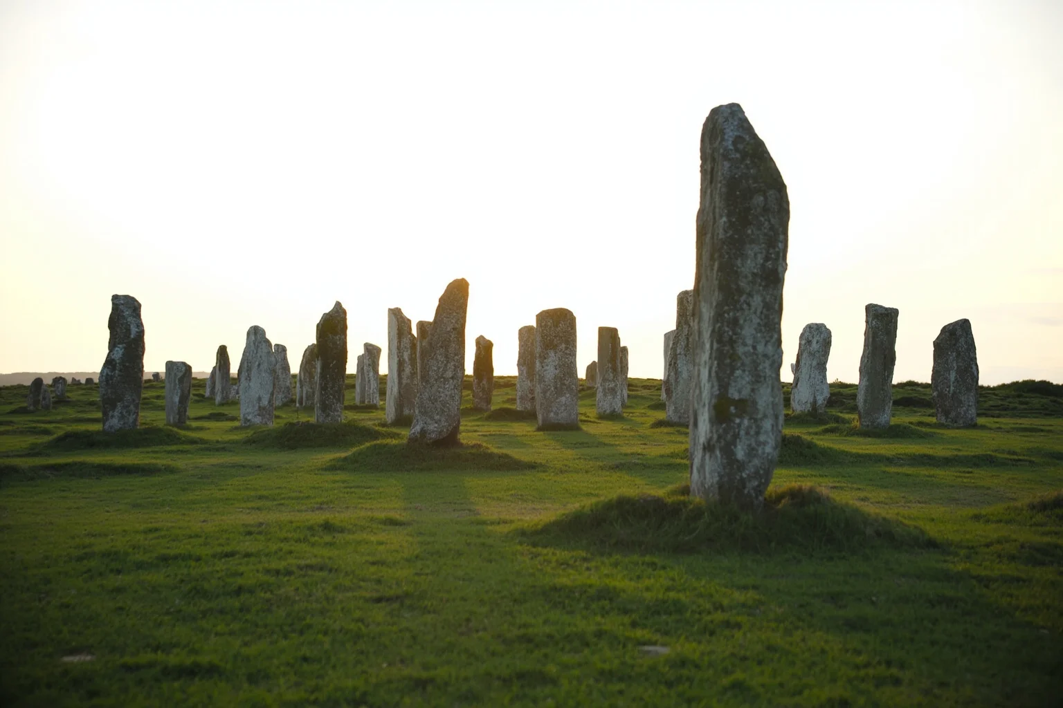 22 Oldest Monuments Found Around the World 6 Rows of standing stones at Carnac in Brittany, France, stretching across a green field under a pale sky