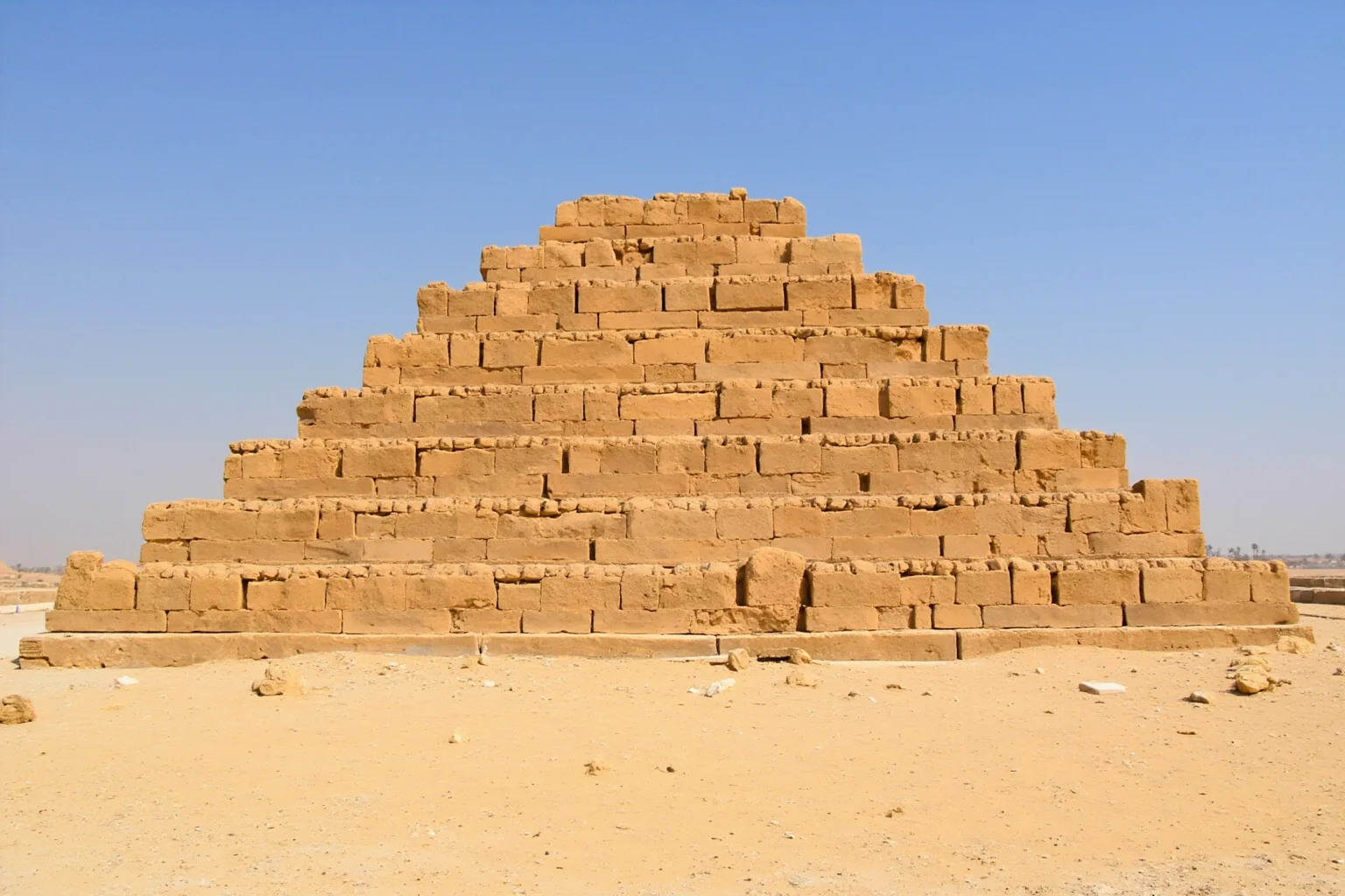 22 Oldest Monuments Found Around the World 17 Step pyramid of Djoser at Saqqara, Egypt, showing six-tiered stone structure against desert sky