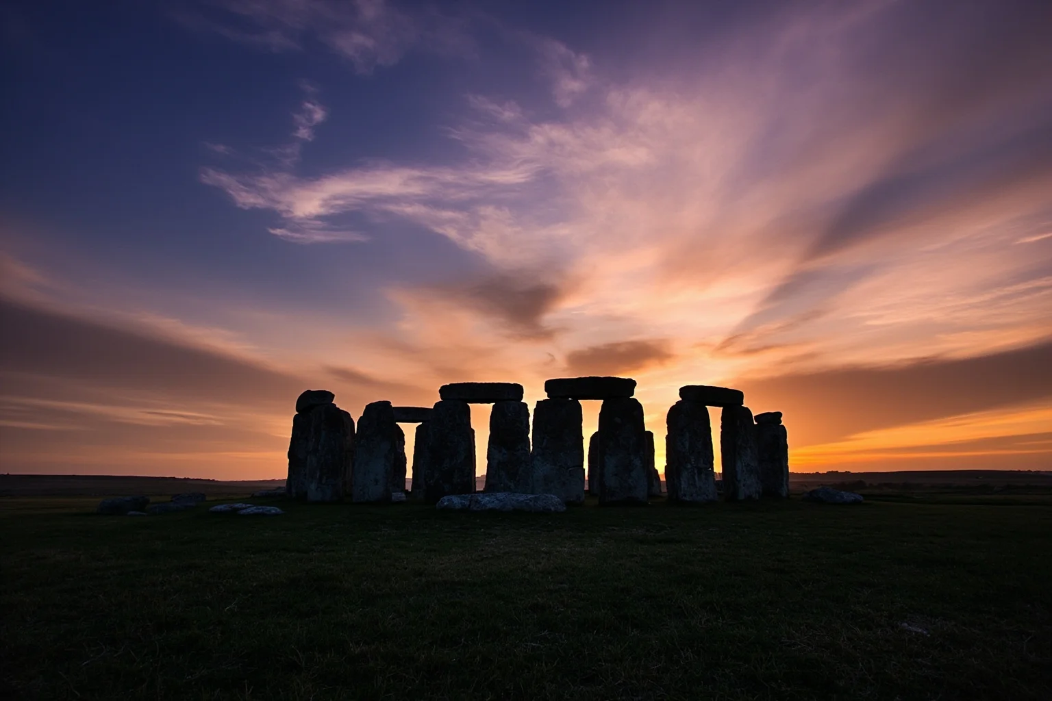 Stonehenge's sarsen circle on Salisbury Plain under a dramatic sunset sky, open grassland around it