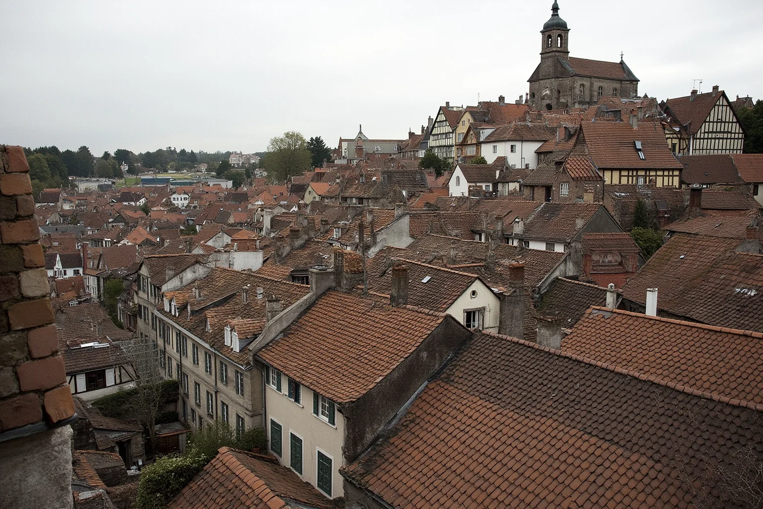 Old Money: 24 Hidden Dynasties That Shaped the Course of History 4 The Fuggerei walled almshouse settlement in Augsburg, terraced medieval houses with a small church, overcast daylight, no people, documentary architecture photography.