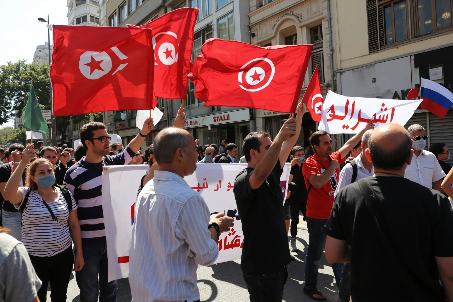 21 Times Governments Were Overthrown by the People 17 Tunisian protesters in Tunis, 2011, street scene, Arabic signs and banners, bright daylight, documentary photography style.
